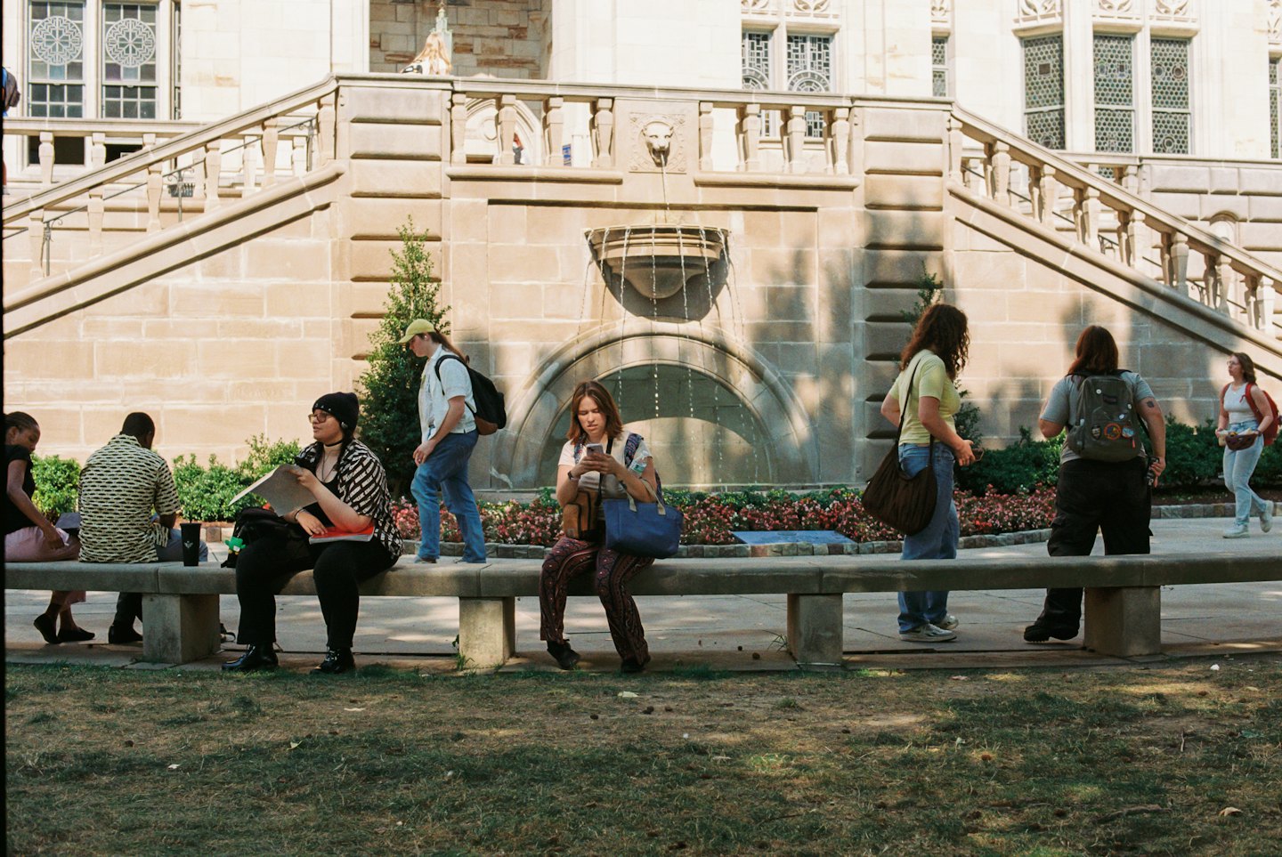 Students gather on the stone steps of a university building.